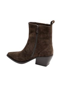 Bottine en daim marron avec fermeture éclair latérale, bout pointu, tirette à l'arrière et talon épais de hauteur intermédiaire.