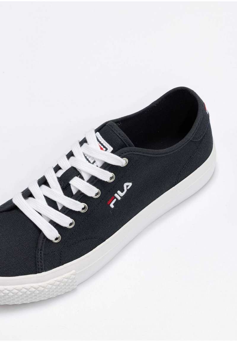 Deportiva negra de lona con cordones blancos, suela de goma y logotipo bordado. Presenta puntera redondeada y lateral texturizado para mayor tracción.