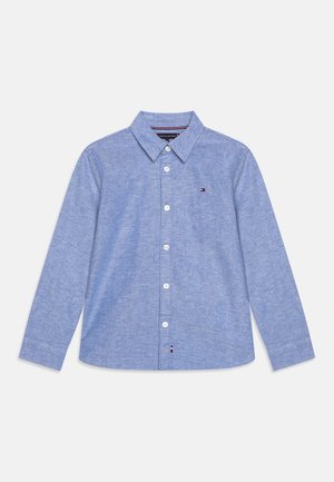 Light blue button-up shirt made of woven fabric, featuring a pointed collar, long sleeves, and a small logo on the chest.