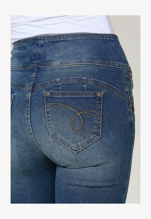 Siniset farkut, joissa on korkea vyötärö. Takana on kaksi taskua, joissa on koristeellinen keltainen tikkauskuvio. Materiaali on sileää ja siinä on kuluneita elementtejä.