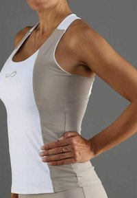Top deportivo en blanco y beige con un ajuste ceñido, que presenta tirantes finos y un escote curvado, realzado con un sutil logotipo en el pecho.
