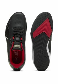 Chaussures de sport noires avec un dessus perforé, une doublure rouge et une semelle en caoutchouc texturée présentant un accent diagonal rouge. Design léger et élancé.