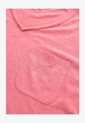 Rosa Baumwoll-T-Shirt mit V-Ausschnitt und einer einzelnen Brusttasche mit sichtbaren Nähten. Der Stoff hat eine weiche, strukturierte Oberfläche.