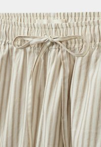 Elastīga josta ar auklu, gaiši bežīga auduma izstrādājums ar vertikālām svītrām gaiši brūnā krāsā, mīksta tekstūra. Redzamie šuvju detaļas.