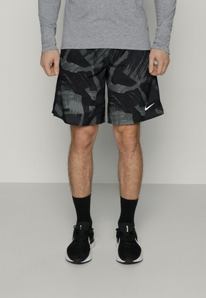 Black and grey patterned athletic shorts made of lightweight fabric, with a small white Nike logo on the lower hem, paired with black shoes.