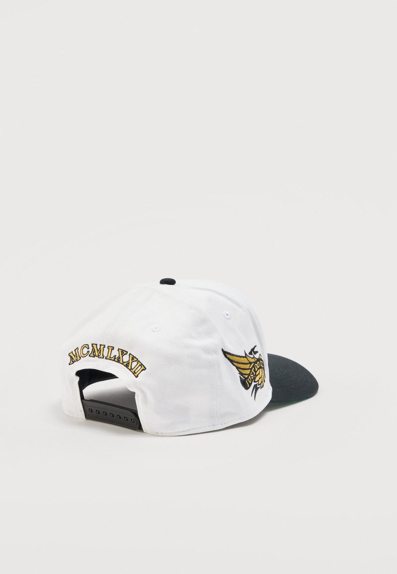 Weißer und schwarzer Snapback-Cap mit goldenem Flügel-Emblem und auf dem hinteren Teil des Caps gesticktem Text sowie römischen Ziffern MCMLXXII.