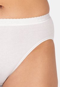 Slip in cotone bianco con elastico ondulato e logo discreto. Il tessuto sembra liscio con un design aderente e copertura laterale.