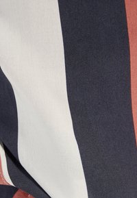 Tkanina w paski o ciemnogranatowych, białych i rdzaawych kolorach. Gładka faktura z pionowymi paskami o różnej szerokości. Lekki materiał bawełniany.