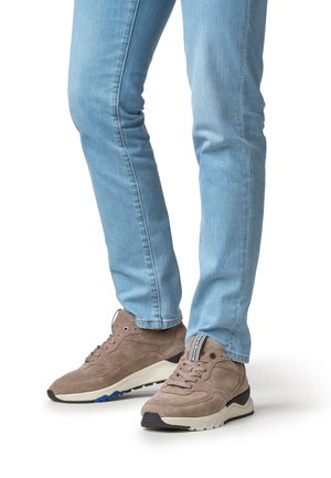 Baskets en daim marron avec une semelle superposée, comprenant des accents noirs et un tissu rayé au talon, associées à un jean skinny bleu clair.