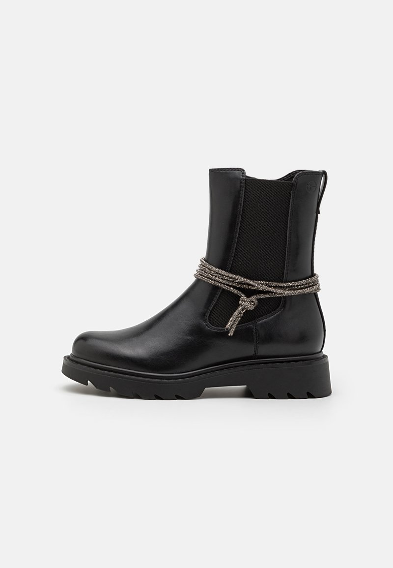 Bottine en cuir noir avec panneaux latéraux élastiques, semelle épaisse et corde argentée décorative nouée autour de la cheville.