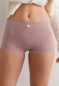 Roze geribbelde shorts met een delicate kantafwerking en een klein wit strikdetail bij de tailleband, gemaakt van zacht, lichtgewicht materiaal.