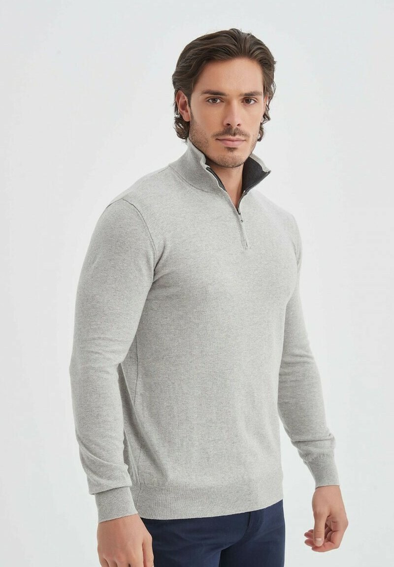Sweat-shirt zippé gris clair avec un col haut, des poignets et un ourlet côtelés. Texture douce et coupe structurée, avec un intérieur gris foncé au niveau du col.