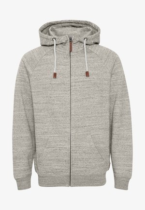 Sivá zip-up kapuca s teksturirano tkanino, prilagojenimi manšetami, nastavljivimi vrvicami in dvema sprednjima žepoma. Rjavi detajli na koncih vrvic.