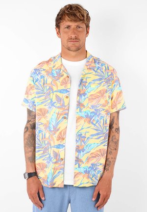 Chemise à manches courtes en jaune pastel avec un motif de feuillage tropical en orange et bleu. Elle possède une poche poitrine et une coupe décontractée.