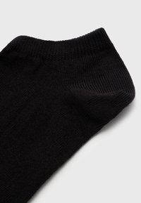 Chaussette noire jusqu'à la cheville avec une texture lisse et un manchon côtelé. Le matériau semble doux et extensible, conçu pour le confort et l'ajustement.