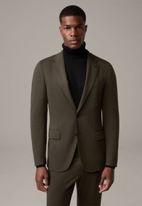 Olivgrüner Blazer mit slim fit, kombiniert mit einem schwarzen Rollkragenpullover. Verfügt über Reverskragen, zwei Fronttaschen und einen einreihigen Knopfverschluss.