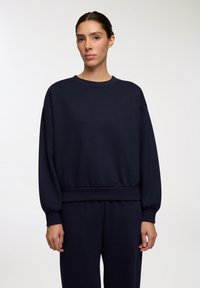 Granatowy sweatshirt wykonany z miękkiego materiału, z okr�ągłym dekoltem, długimi rękawami z ribbowymi mankietami oraz ribbowym wykończeniem dołu.