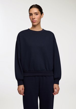 Felpa blu navy realizzata in tessuto morbido, con scollatura rotonda, maniche lunghe con polsini a costine e orlo a costine.