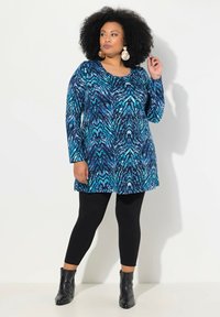 Tunic a maniche lunghe con stampa astratta blu e teal abbinata a leggings neri e stivaletti, con scollo rotondo e vestibilità rilassata.