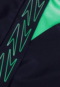 Tessuto navy con un accento verde, liscio e motivo a zigzag. Progettato con texture contrastanti e vivaci giochi di colori.