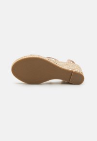 Woven espadrille sole in natural color with a textured surface. Light brown rubber outsole, featuring a smooth, rounded edge.