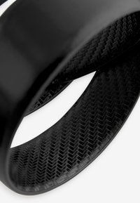 Czarna gumowa bransoletka o teksturowanym, plecionym wzorze. Gładki, elastyczny materiał z błyszczącym wykończeniem i subtelnymi refleksyjnymi akcentami.