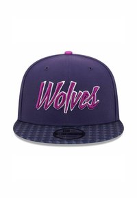 Purple snapback cap featuring "Wolves" embroidered in white and pink on the front, with a textured patterned brim.