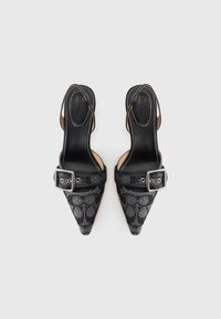 Fekete hegyes orrú pántos cipők ezüst csatokkal és texturált mintával, erős sarokkal, és a talpbetéten "Coach" logóval, felülről nézve.