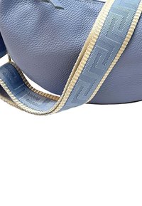 Lichtblauwe leren handtas met een gestructureerde afwerking, voorzien van een gestreepte blauwe en beige schouderband. Ronde vorm, minimale hardwareaccenten.