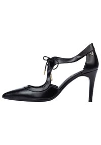 Zapato de tacón alto de cuero negro con punta afilada, lados recortados y detalle de lazo. Presenta acentos dorados y un tacón delgado.