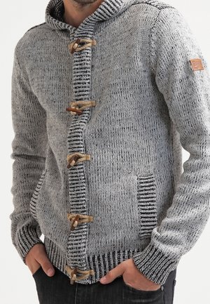 Grau gestrickte Strickjacke mit Kapuze, ausgestattet mit hölzernen Knopfverschlüssen, kontrastierenden gerippten Bündchen und Seitentaschen. Strukturierter Stoff mit Streifen.