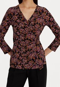 Svart blommig omslagstopp med trekvartsärmar, prydd med rosa och orange blommor och blad, mjuk textur och en sida med knytning.