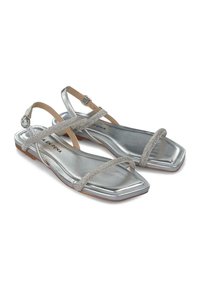 Sandalias planas de metal plateado con tiras cruzadas y acentos de rhinestones, que presentan un diseño de punta cuadrada y una suela plana de goma.