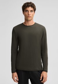 Langsleeve crewneck shirt in donkergroen, gemaakt van gestructureerde stof. Heeft een ontspannen pasvorm en een eenvoudig, ongecompliceerd ontwerp.