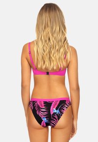 Zestaw bikini z jaskraworóżowym stanikiem z regulowanymi ramiączkami, w połączeniu z czarnymi majtkami ozdobionymi kolorowymi, tropikalnymi wzorami liści.