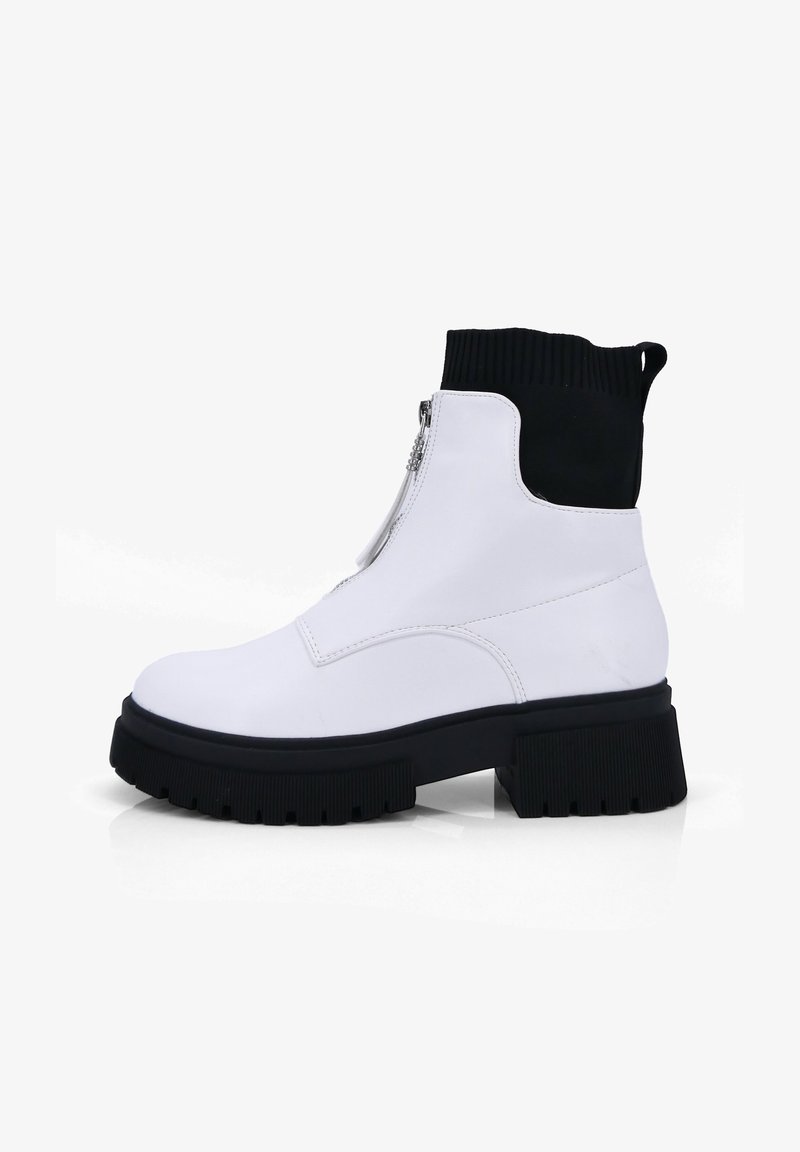 Witte enkelboots met een zwarte elastische manchet, een zijrits, een stevige zwarte zool en een gladde, leerachtige textuur. Modern ontwerp met contrasterende kleuren.