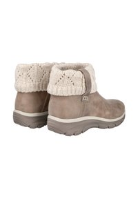 Botas de ante marrón hasta el tobillo con suelas de goma gruesas y puños de punto beige doblados, mostradas desde ángulos trasero y lateral.