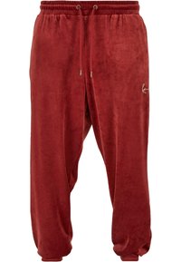 Röda sammetsträningar med elastisk midja, snörning och ribbade ärmslut. Har en sidologotyp i vitt. Mjuk känsla och lös passform.