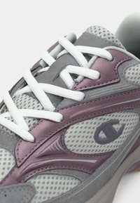 Γκρι και μωβ αθλητικό παπούτσι με λευκά κορδόνια, ύφασμα από δίχτυ και στυλιζαρισμένο λογότυπο "C" στην πλευρά.