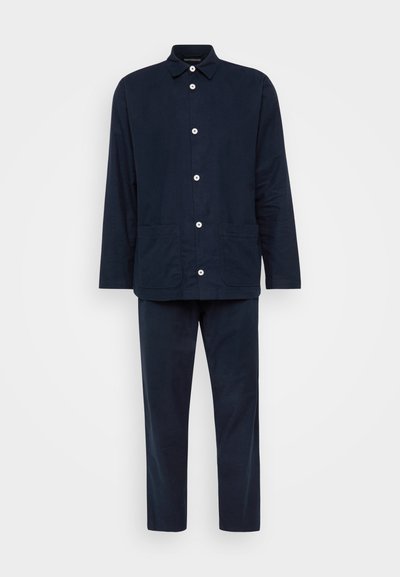Conjunto em azul marinho composto por uma camisa de botão de manga longa com colarinho e dois bolsos frontais, combinada com calças a condizer.
