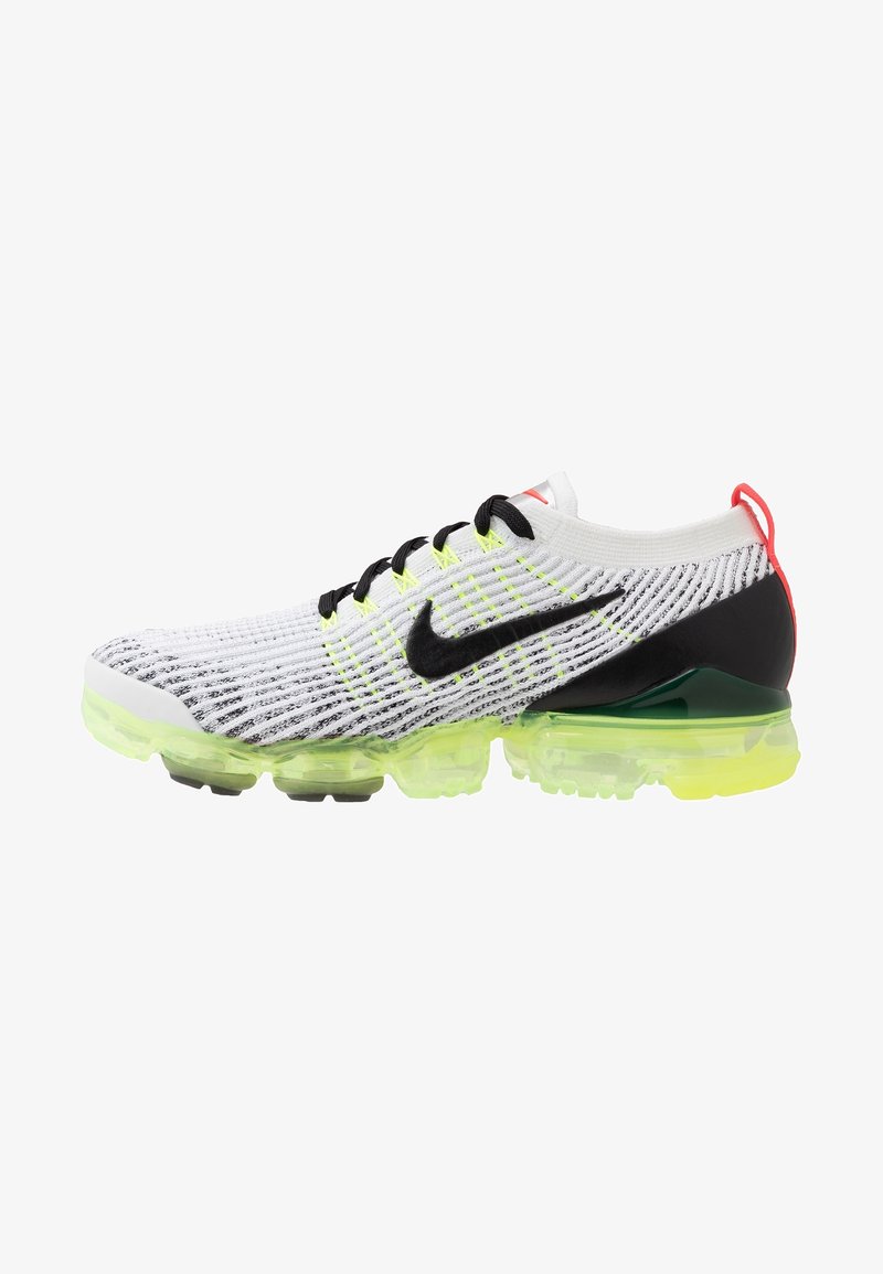 Chaussure de course Nike blanche et noire avec semelle amortie jaune fluo, swoosh noir, lacets noirs et languette rouge au talon.