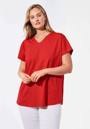 Rode katoenen T-shirt met een V-hals en korte mouwen, relaxte pasvorm, zachte textuur, gedragen met witte broek. Eenvoudig en klassiek in ontwerp.