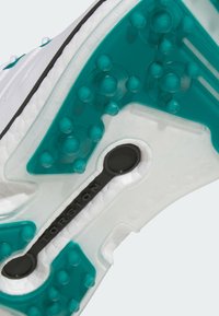 Biała podeszwa sportowego buta z przezroczystą tealowym spodem, teksturowanymi punktami do gripu oraz czarnym urządzeniem "TORSION" do integracji stabilności.