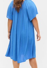 Blå klänning med korta ärmar och avslappnad passform, tillverkad av lätt krepptyg, med rundad halsringning och svävande nederkant.
