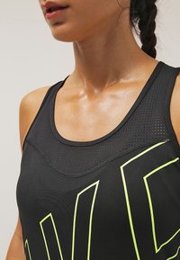 Černé sportovní tílko s síťovinou u výstřihu, výrazným neonově žlutým grafickým motivem a přiléhavým střihem.