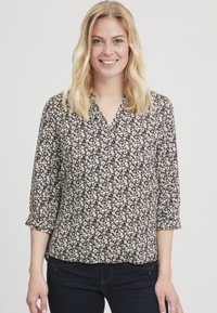 Bloes met bloemenprint, V-hals, driekwartmouwen, op een donkere achtergrond met kleine witte, gele en bruine bloemen op een zachte stof.