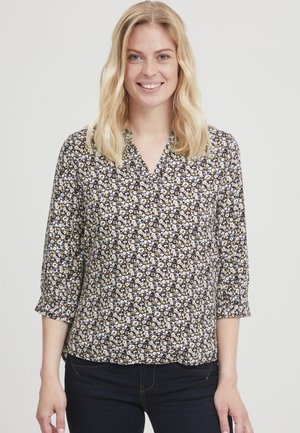 Blus med blommigt mönster, V-ringning, trekvartslånga ärmar, mörk bakgrund och små vita, gula och bruna blommor på ett mjukt tyg.