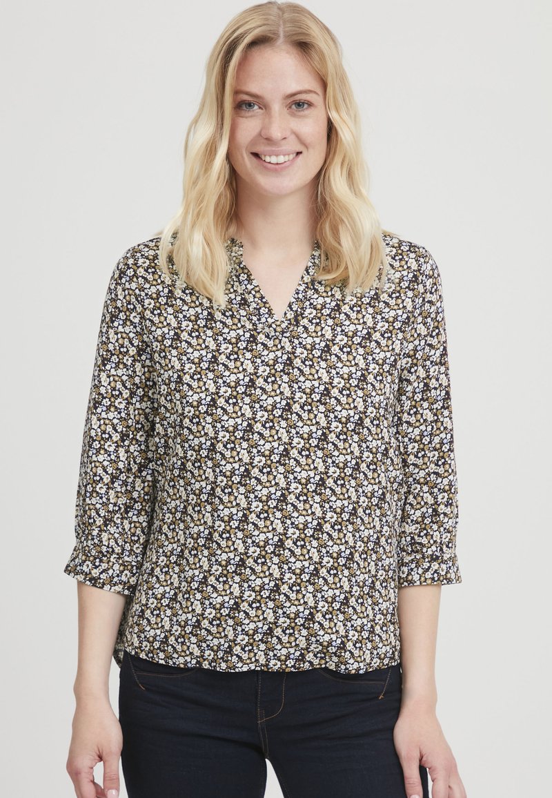 Bloes met bloemenprint, V-hals, driekwartmouwen, op een donkere achtergrond met kleine witte, gele en bruine bloemen op een zachte stof.