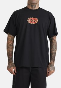 Zwarte katoenen t-shirt met korte mouwen, voorzien van een rood en gouden grafisch ontwerp op de borst. Relaxte pasvorm en een soepele textuur.