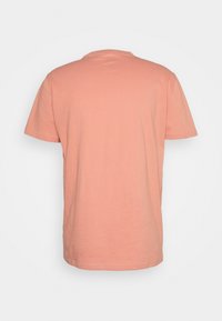 T-shirt à manches courtes de couleur saumon, affiché de dos sur un fond blanc.